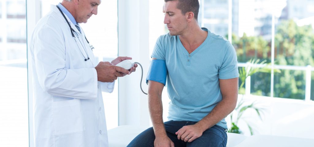 Doctor examining his patients blood pressure in medical office